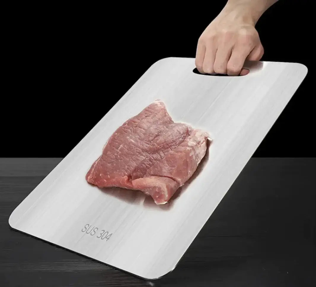 Et skærebart der har en steak læggende oven, hvor der er en hånd der holder og holder skærebrættet oven på